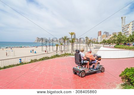 Benidorm, Spain, 17 June, 2019: Senior Couple On Mobility Scooter Enjoying Summer Vacation In Benido