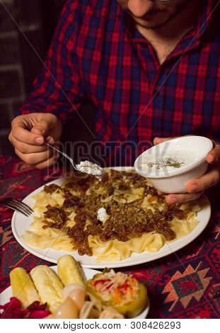 Man Adding Yogurt To Caucasian Traditional Food, Khinkali, Khingal Served With Turshu. Image