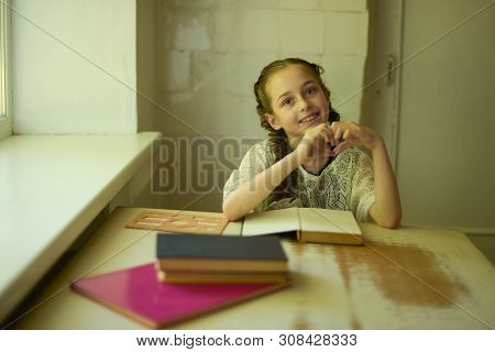 Pupil In School Uniform With Braids. Girl Schoolgirl At School With Book In School Uniform. Training