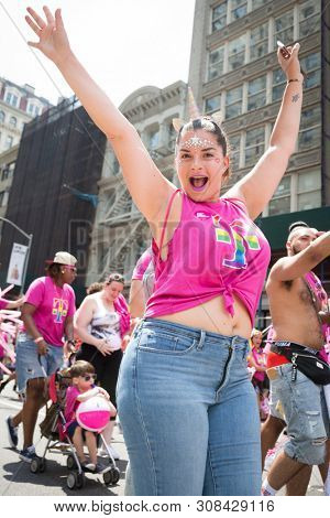 2018 JUNE 24 NEW YORK: NYC Pride March participants wearing pink and rainbow colored T-Mobile shirts walk along the 5th Ave parade route.