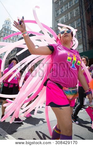 2018 JUNE 24 NEW YORK: NYC Pride March participants wearing pink and rainbow colored T-Mobile shirts walk along the 5th Ave parade route.
