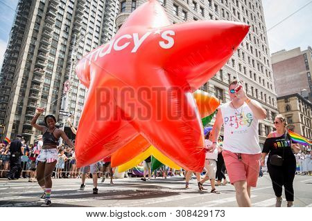 2018 JUNE 24 NEW YORK: NYC Pride March participants hold the Macys Pride and Joy balloons on the 5th Ave parade route.