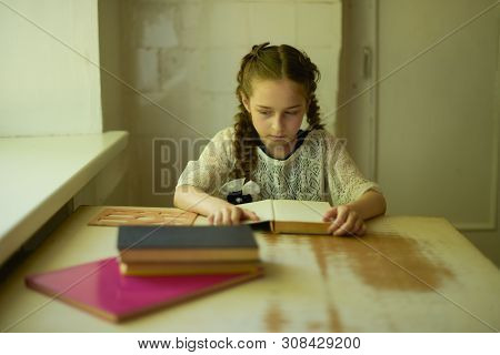 Pupil In School Uniform With Braids. Girl Schoolgirl At School With Book In School Uniform. Training