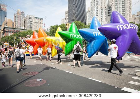 2018 JUNE 24 NEW YORK: NYC Pride March participants hold the Macys Pride and Joy balloons on the 5th Ave parade route.