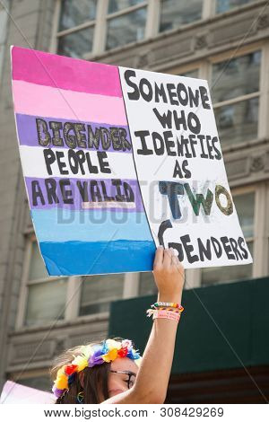 2018 JUNE 24 NEW YORK: NYC Pride March participant holds a sign that says BiGender People Are Valid on the 5th Ave parade route.