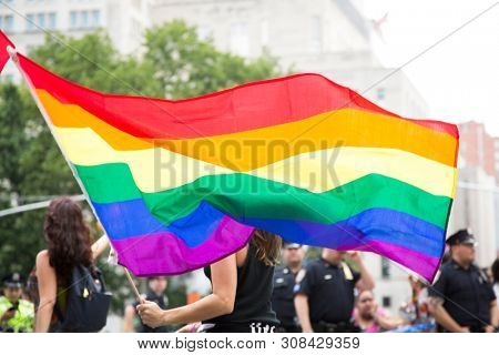 2018 JUNE 24 NEW YORK: NYC Pride March participants wave rainbow flags as they walk along the parade route on 5th Ave.