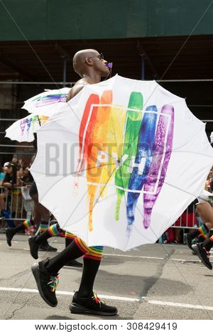 2018 JUNE 24 NEW YORK: NYC Pride March participants walk with colorful rainbow umbrellas at 23rd St and 5th Ave.