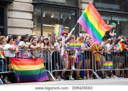 2018 JUNE 24 NEW YORK: NYC Pride March spectators wave rainbow flags and cheer the participants at 23rd St and 5th Ave.
