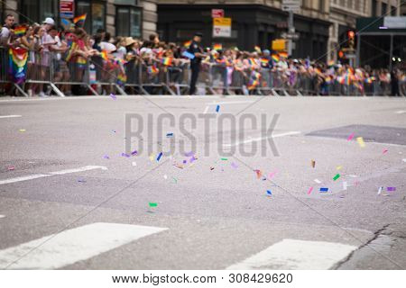 2018 JUNE 24 NEW YORK: Colorful confetti in the street while NYC Pride March spectators wave rainbow flags at 23rd St and 5th Ave.