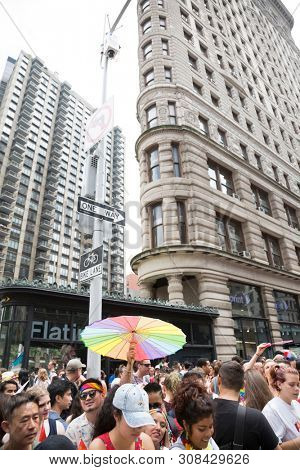 2018 JUNE 24 NEW YORK: NYC Pride March participants walk with colorful rainbow umbrellas at 23rd St and 5th Ave.