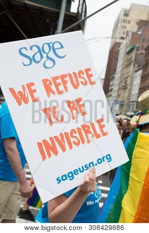 2018 JUNE 24 NEW YORK: NYC Pride March Sage participant holds a sign that says We Refuse To Be Invisible on the 5th Ave parade route.
