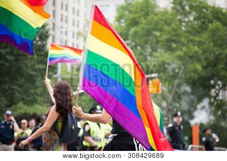 2018 JUNE 24 NEW YORK: NYC Pride March participants wave rainbow flags as they walk along the parade route on 5th Ave.