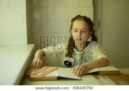 Pupil In School Uniform With Braids. Girl Schoolgirl At School With Book In School Uniform. Training