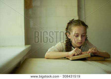 Pupil In School Uniform With Braids. Girl Schoolgirl At School With Book In School Uniform. Training