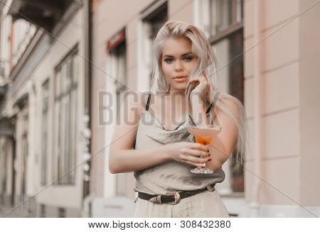 Young Beautiful Woman Is Enjoying Her Drink While Posing For Photographer.