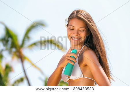 Sunscreen sun tan lotion against sunburn. Asian woman spraying mosquito spray bottle on body for zika virus on Caribbean beach.