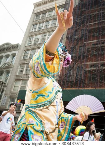 2018 JUNE 24 NEW YORK: NYC Pride March participants wearing an Asian inspried with a fan outfit walks along the 5th Ave parade route.