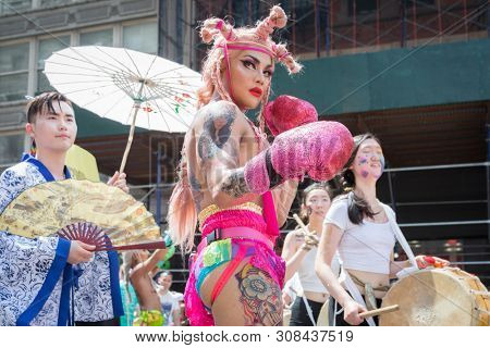 2018 JUNE 24 NEW YORK: NYC Pride March participant wearing pink boxing gloves and high heel boots walks along the 5th Ave parade route.