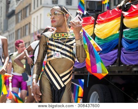 2018 JUNE 24 NEW YORK: NYC Pride March participant wearing a black and gold striped see-through outfit walks along the 5th Ave parade route.
