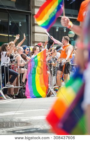 2018 JUNE 24 NEW YORK: NYC Pride March participants wave rainbow flags as they walk along the parade route on 5th Ave.