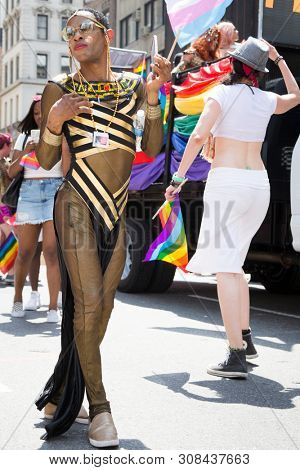 2018 JUNE 24 NEW YORK: NYC Pride March participant wearing a black and gold striped see-through outfit walks along the 5th Ave parade route.