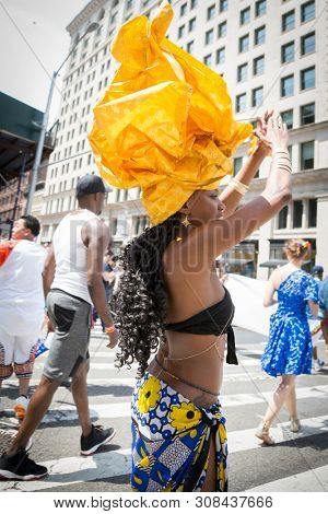 2018 JUNE 24 NEW YORK: NYC Pride March participant wearing a tribal outfit with yellow headwear walks along the 5th Ave parade route.