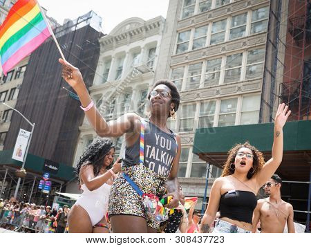 2018 JUNE 24 NEW YORK: NYC Pride March participants wave rainbow flags as they walk along the parade route on 5th Ave.