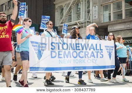 2018 JUNE 24 NEW YORK: NYC Pride March participants walk behind a Stonewall Democrats banner on the 5th Ave parade route.
