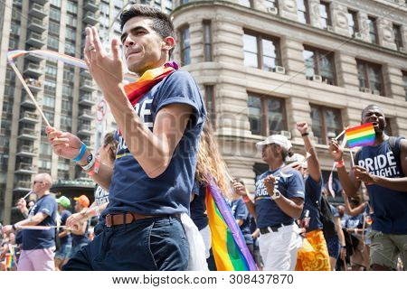 2018 JUNE 24 NEW YORK: NYC Pride March participant wearing a Pride Flight tshirts and rainbow cape walks along the 5th Ave parade route.