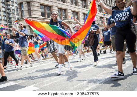 2018 JUNE 24 NEW YORK: NYC Pride March participants wave rainbow flags as they walk along the parade route on 5th Ave.