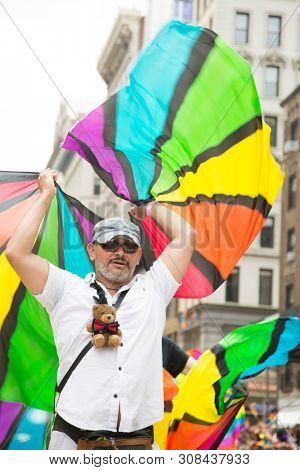2018 JUNE 24 NEW YORK: NYC Pride March participants wave rainbow flags as they walk along the parade route on 5th Ave.