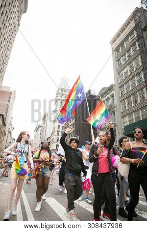 2018 JUNE 24 NEW YORK: NYC Pride March participants wave rainbow flags as they walk along the parade route on 5th Ave.