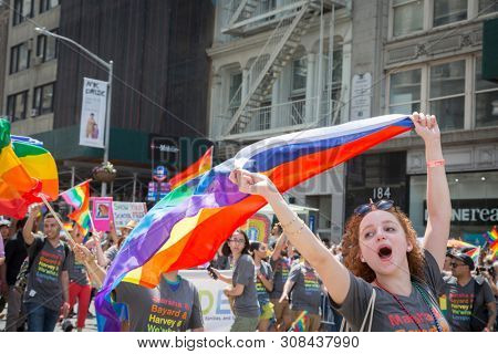 2018 JUNE 24 NEW YORK: NYC Pride March participants wave rainbow flags as they walk along the parade route on 5th Ave.