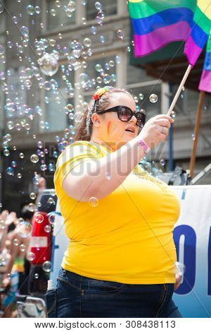 2018 JUNE 24 NEW YORK: NYC Pride March participants wave rainbow flags as they walk along the parade route on 5th Ave.