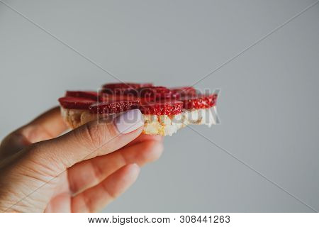 Crispbread With Strawberries In Hand On A Gray Background