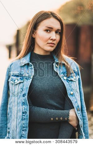 Portrait Of The Attractive, Slender, Beautiful Young Caucasian Blonde Girl In A Jeans Jacket. Smilin