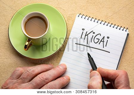 ikigai, a reason for being - man hand writing a note with a black marker in a spiral notebook