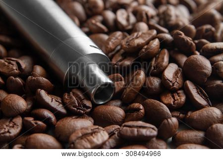 Coffee Flavor E-juice Concept. Handheld Vape Device On The Background Of Soft Focused Coffee Beans