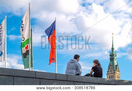 Hamburg, Germany - July 23, 2017: A Young Couple In  Jungfernstieg Stret With Flags And The Town Hal