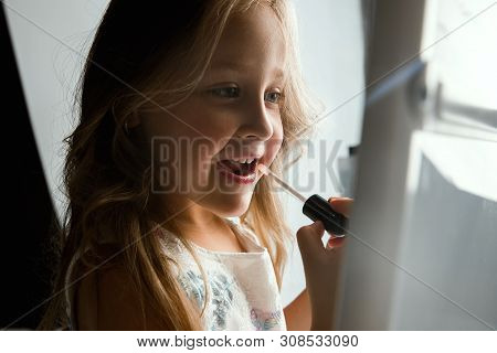 Interaction Of Children With Adult World. Cute Girl Trying To Do Bright Make Up For Being Older. Lit