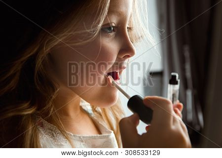 Interaction Of Children With Adult World. Cute Girl Trying To Do Bright Make Up For Being Older. Lit