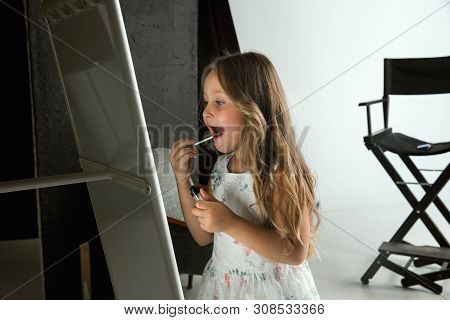 Interaction Of Children With Adult World. Cute Girl Trying To Do Bright Make Up For Being Older. Lit