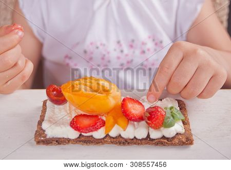 Crisp Bread With Creme Cheese, Fruit And Berries In The Childs Hand