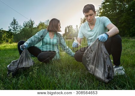 Friends Crouching With Bag Picking Up Trash Doing Plogging.plogging Concept. Boy And Girl Picking Up