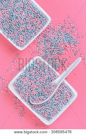 Colorful Nonpareils Cake Candy Sprinkles In Two White Rectangular Bowls And Spoon On Pink Background