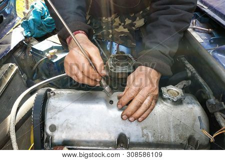 The Car Mechanic Unlocks The Motor Cover Of An Old Car And Will Repair It.