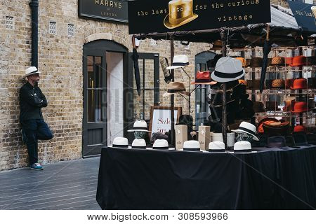 London, Uk - June 22, 2019: Man Behind Hats On Sale At A Stall Inside Spitalfields Market, One Of Th
