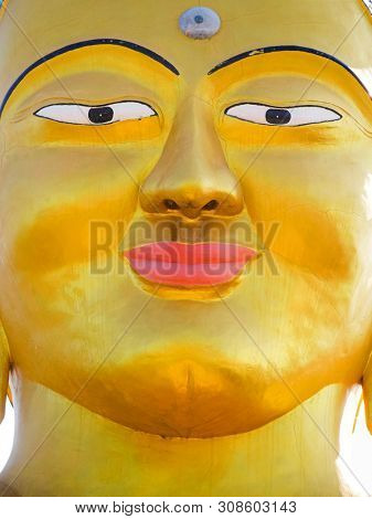 Closeup vibrant gold Shanti Ban Buddha face, 25 feet tall golden Buddha's image on a sunny day in Dhulikhel, Nepal 