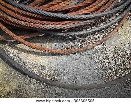 Old Rusty Strong Cable Rolled Into The Bay. The Rings Of Iros Are Located On The Ground, The Yard Of