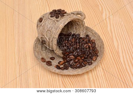Coffee Beans In A Decorative Cup And Saucer On The Wooden Surface.